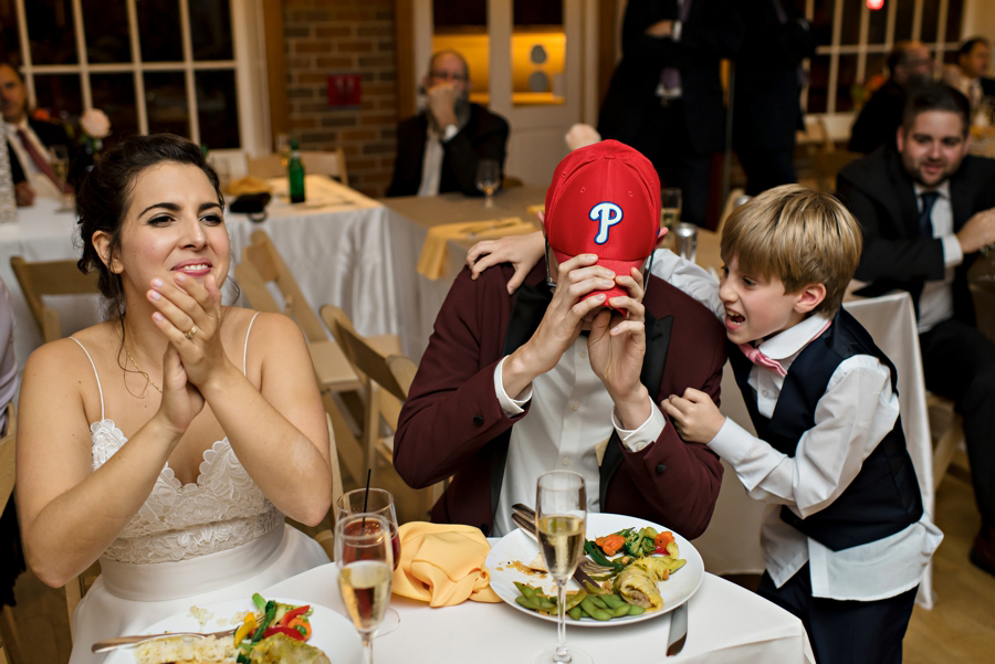 The groom putting on a Phillies hat during his wedding reception.